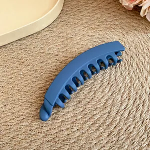 Gros plan d'une pince à cheveux banane bleu mat sur un fond en paille tressée