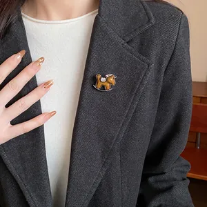 Detailed view of a vintage rocking horse brooch pinned to a dark blazer lapel style.