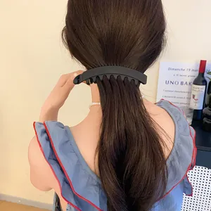 Gros plan d'une pince à cheveux en acrylique noir mat tenant une queue de cheval élégante