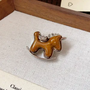 Close-up detail of a minimalist rocking horse brooch with glitter resin and rhinestone accents