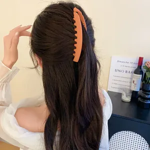 Gros plan détaillé d'une pince à cheveux orange givré en acrylique sur cheveux foncés