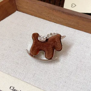 Close-up of a brown flocked rocking horse brooch with sparkling rhinestone accents