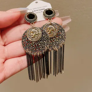 Close-up of vintage gold tassel earrings with intricate filigree and human relief
