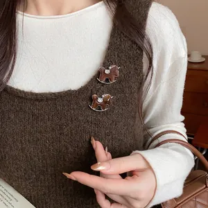 Detail of two resin rocking horse brooches with rhinestone accents on a brown knit vest