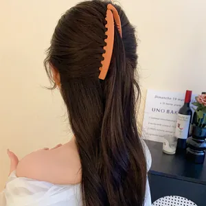 Vue arrière d'une pince à cheveux banane orange mate sur de longs cheveux sombres