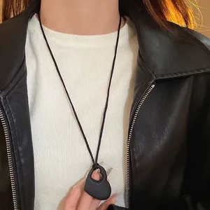Collier minimaliste avec pendentif cœur noir mat porté avec une veste en cuir