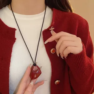 Collier pendentif cœur évidé rouge minimaliste sur une longue chaîne de pull noire pour femme