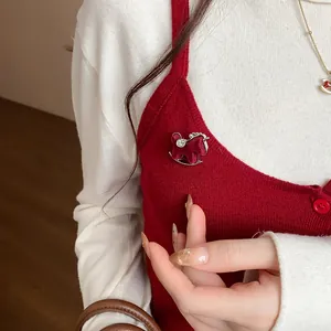 Detail of a maroon flocked rocking horse brooch with sparkling rhinestones on red knitwear