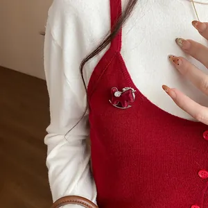 Macro view of a red flocked resin pony brooch with rhinestone on a red knitted vest