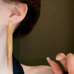 Detailed view of gold tassel snake chain earrings worn on ear showing elegant drape