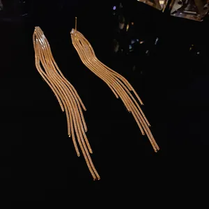 Detail view of elegant gold tassel earrings featuring fluid multi-strand snake chains