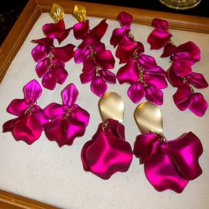 Dettaglio di orecchini a nappa con petali fucsia vibranti e accenti in metallo dorato.
