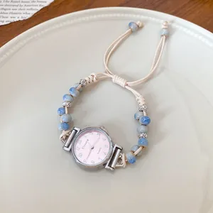 Detailed view of a wax rope woven bracelet with a pink quartz watch and ceramic beads.