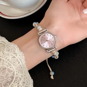 Close-up of a pink dial quartz watch with marbled ceramic beads and woven wax cord strap.