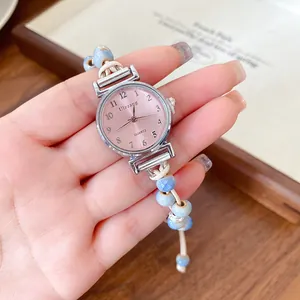 Detailed shot of a dainty watch with pink dial and blue ceramic bead braided strap