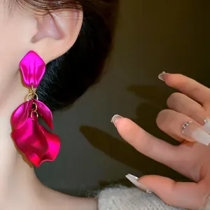 Primo piano di orecchini con nappa a petali fucsia vibranti su una modella elegante.