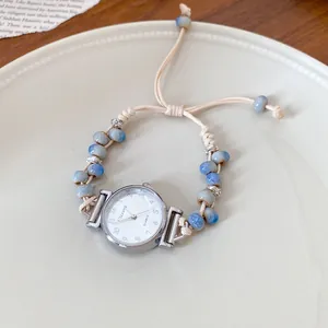 Detail view of a stylish quartz watch with hand-woven cord and blue ceramic beads
