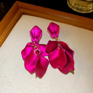 Dettaglio di orecchini a goccia con petali opachi magenta e maglie dorate