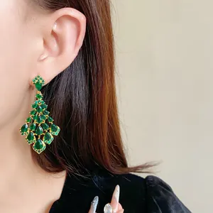 Eleganti orecchini lunghi in zircone verde indossati sull'orecchio di una modella