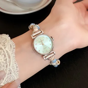 Close-up of a women's quartz watch with a woven wax rope and blue ceramic bead strap.