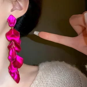Visuale ravvicinata di orecchini a nappa lunga con petali di fiori metallici magenta