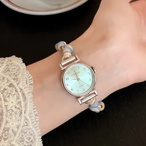 Close-up of elegant women's watch with mint green dial and blue ceramic bead woven strap