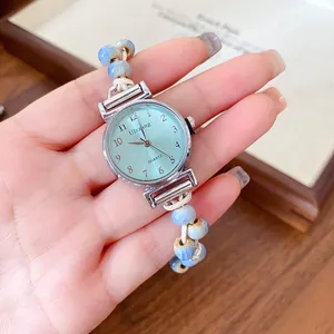 Close-up of a vintage watch with mint green dial and blue ceramic bead bracelet strap.