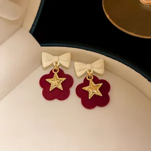 Elegant festive burgundy flocked flower earrings featuring a white bow and gold star charm