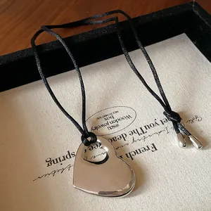 Vue macro détaillée d'un collier pendentif cœur minimaliste sur un cordon de soie noir