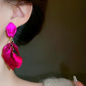 Orecchini pendenti a petalo magenta vibrante indossati sull'orecchio di una modella