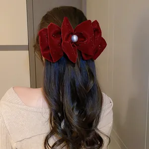 Nahaufnahme einer festlichen roten Samtschleife mit eleganter Perle im gewellten Haar