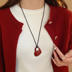 Élégant collier avec pendentif en cœur rouge évidé porté avec un cardigan rouge