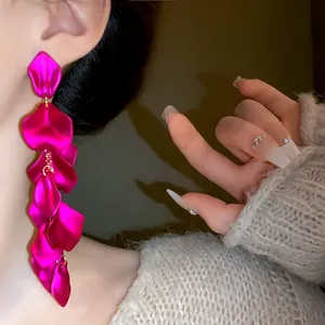 Primo piano dettagliato di lunghi orecchini a nappa a forma di petalo color fucsia vibrante