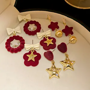 Close-up of various Christmas velvet bow and star earrings in a white jewelry box.