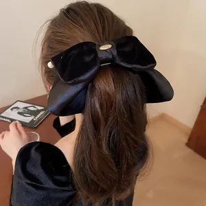 Elegante Rückansicht einer großen schwarzen Samtschleife-Haarklammer mit Perle und Gold
