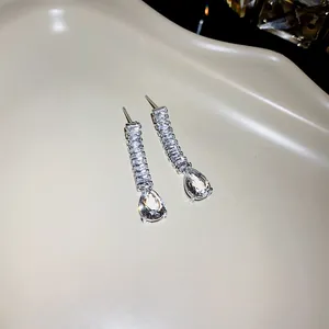 Détail de boucles d'oreilles argentées élégantes avec gouttes de zircone en poire.
