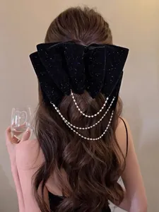 Nahaufnahme der großen schwarzen Samtschleife-Haarspange mit eleganten Perlenketten-Quasten.