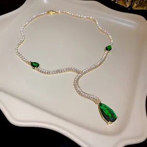 Détail élégant d'un collier luxueux en or en forme de Y avec des cristaux vert émeraude