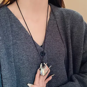 Gros plan d'un collier pendentif cœur évidé en argent sur un pull gris