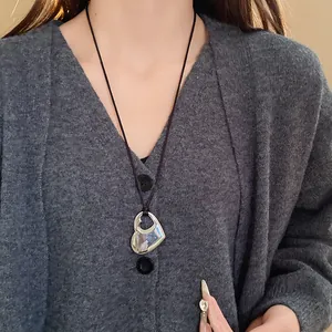 Collier pendentif coeur argenté évidé sur un pull en maille gris pour un look tendance