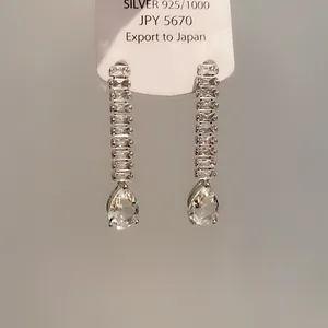 Gros plan d'élégantes boucles d'oreilles argentées avec zircons en forme de poire