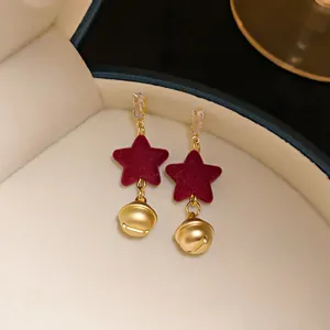 Macro detail of festive red velvet star and golden bell Christmas stud earrings jewelry