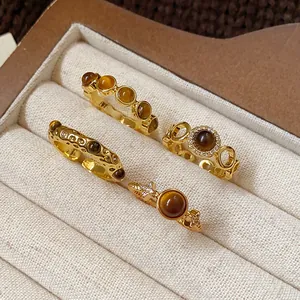 Detail view of four vintage gold-plated rings with natural tiger-eye gemstones