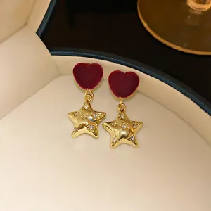Close-up of elegant red velvet heart and gold star drop earrings in jewelry box