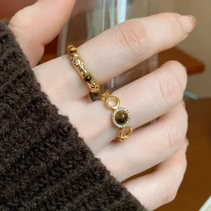 Detailed close-up view of gold-plated rings with tiger eye stones worn on a hand