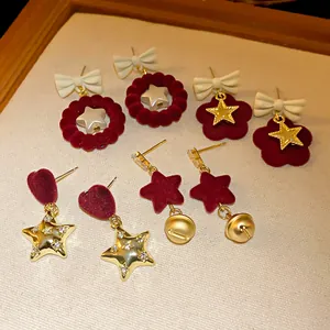 Close-up detail of various festive red velvet bow and golden star earrings for Christmas.