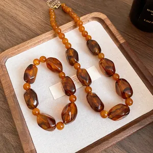 Detail view of retro Maillard amber acrylic irregular beaded necklace on wooden tray
