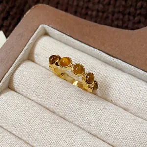 Close-up view of a vintage gold-plated open ring set with five round tiger's eye stones