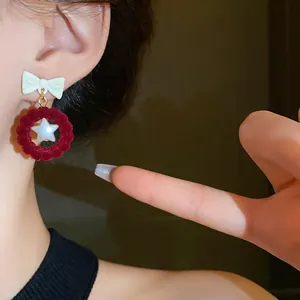 Detailed view of festive red velvet bow-knot earrings with a central star pearl detail