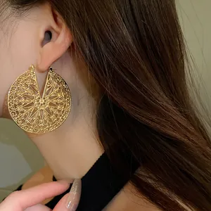 Gros plan détaillé d'une grande boucle d'oreille dorée géométrique sur modèle